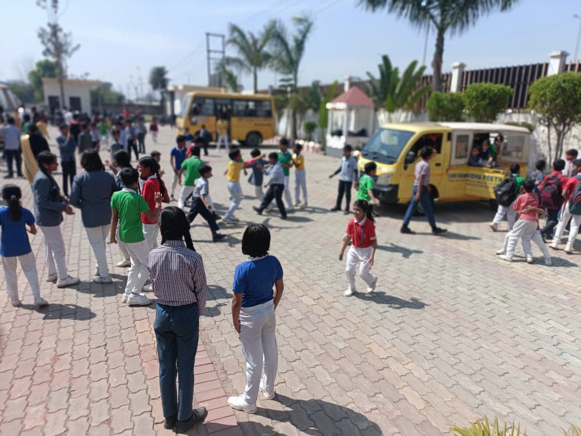 Students celebrating Holi in the school courtyard beside the school buses